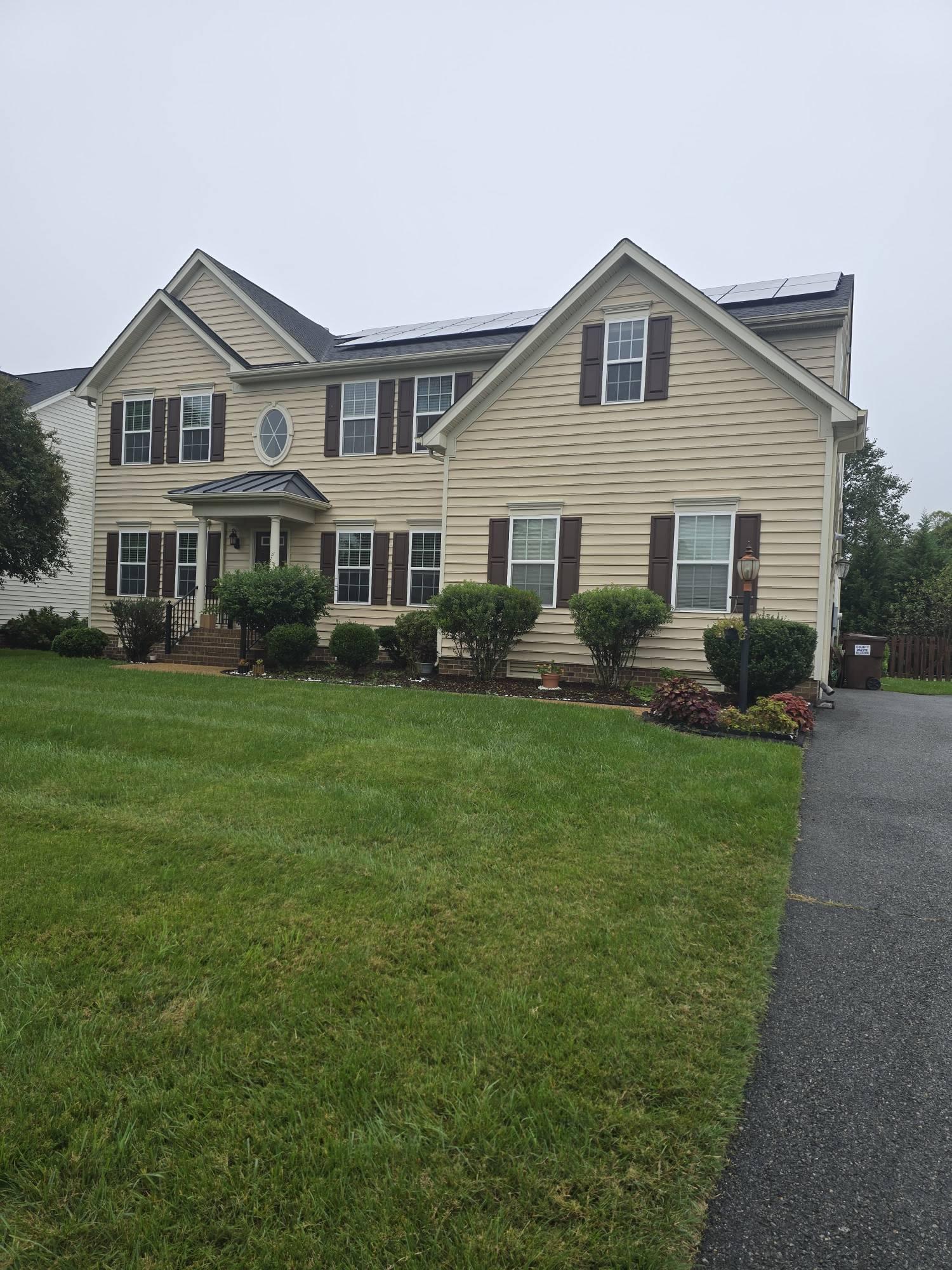 Front of 3536 Hunton Ridge Dr: a two-story home with tan siding, dark shutters and solar panels on the roof